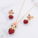 Juego de Collar y Aretes Bañados en Oro con Diseño de Flor de Cerezo Esmaltada y Fresa en Pavé de Circones Rojos